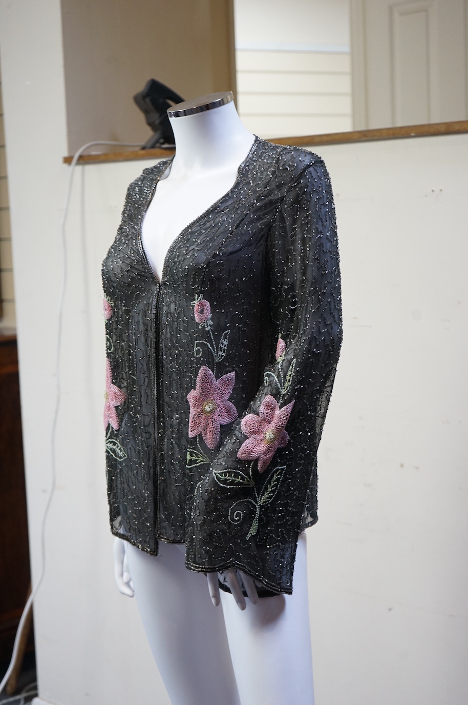 A 1930’s, multi coloured floral hand beaded evening jacket, the beading worked on black georgette. Possibly French, label on the inside of the neck 48. 64cm long. Condition - beading and georgette appear in good conditio